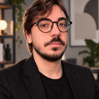 Retrato de Vini Asevedo usando óculos e blazer preto